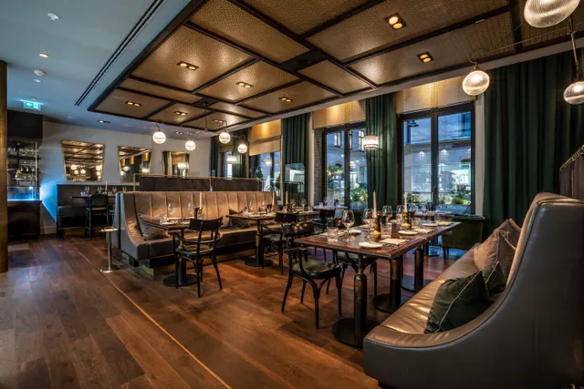 Gedeckte Tische in der Brasserie mit grünen Vorhängen und goldenen Leuchten